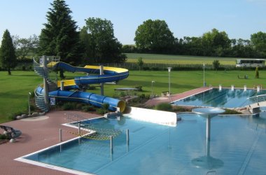 Schwimmerbecken mit Rutsche und Liegefläche im Hintergrund